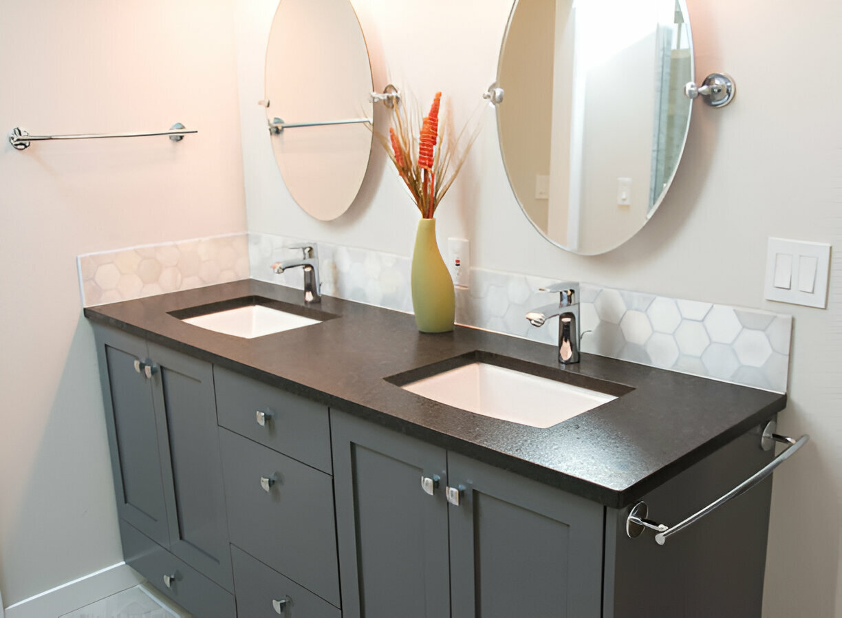 Gray double vanity with dark countertop, hexagon tile backsplash, undermount sinks, and round mirrors in a modern bathroom