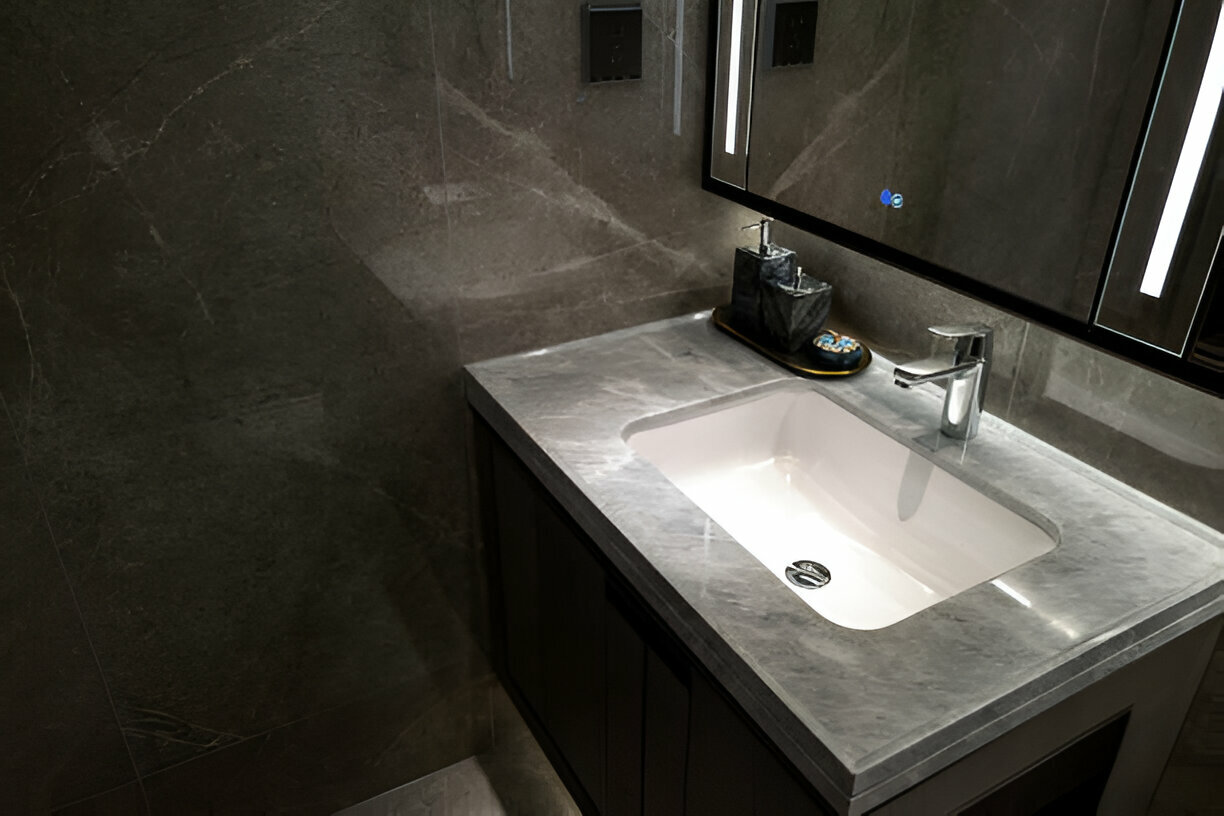 Modern bathroom with a floating vanity, marble countertop, undermount sink, illuminated mirror, and chrome faucet against dark-toned walls
