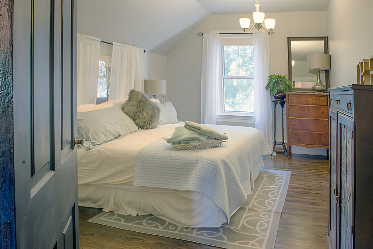 Cozy bedroom with white bedding and vintage wooden furniture