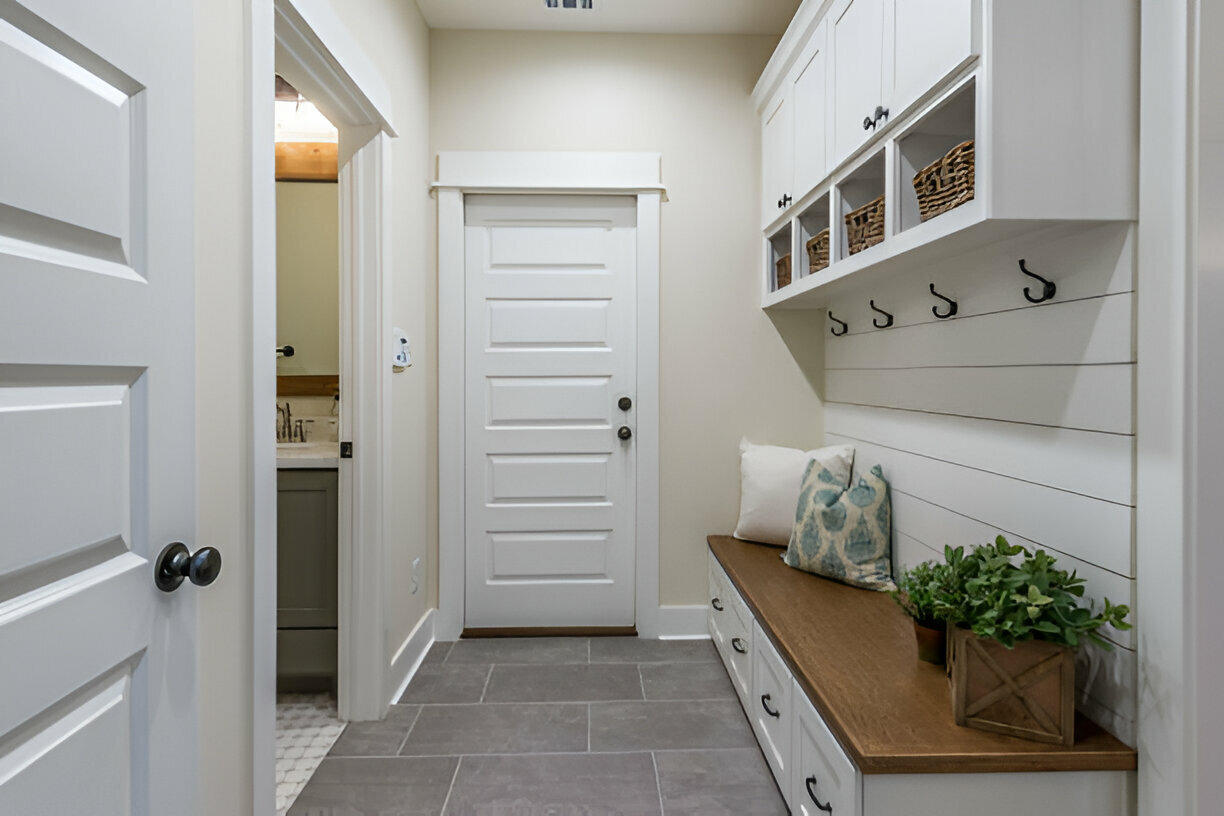 Modern mudroom with built-in white storage cabinets, bench seating, and decorative accents