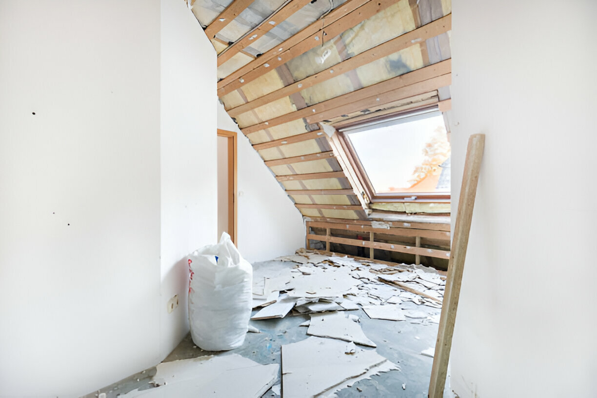Attic room under renovation with exposed insulation and roof window
