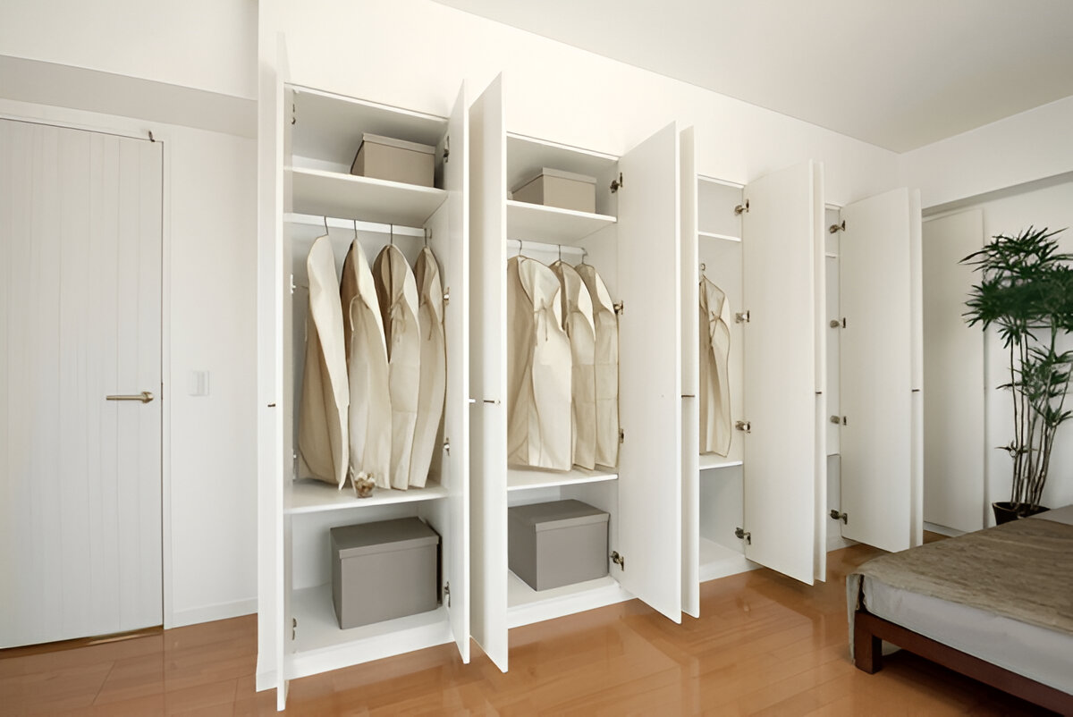 Open white built-in wardrobes with hanging clothes and storage boxes. 