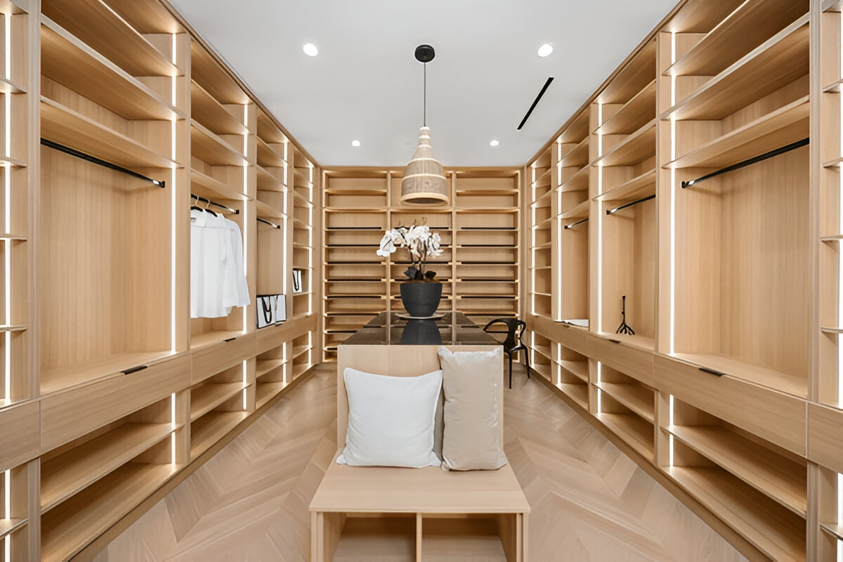 Modern luxury walk-in closet with illuminated wood shelves and a central island.