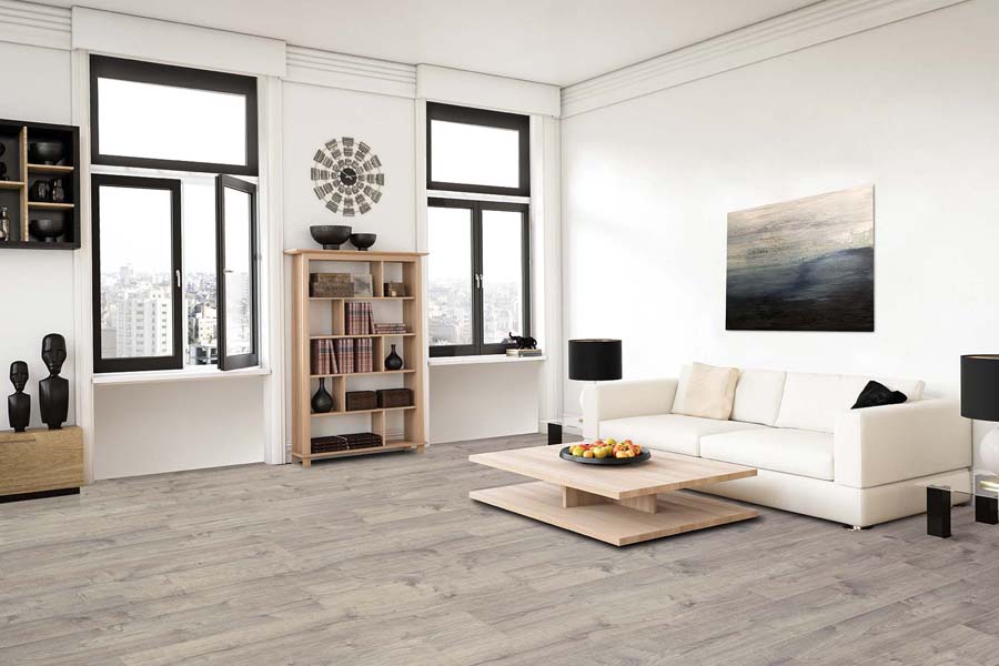 Bright living room with light gray wood flooring, white sofa, large windows with black frames, and light wood coffee table