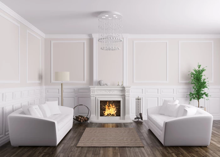 Classic living room featuring two white sofas, a central fireplace, chandelier, and hardwood floors with neutral wall paneling