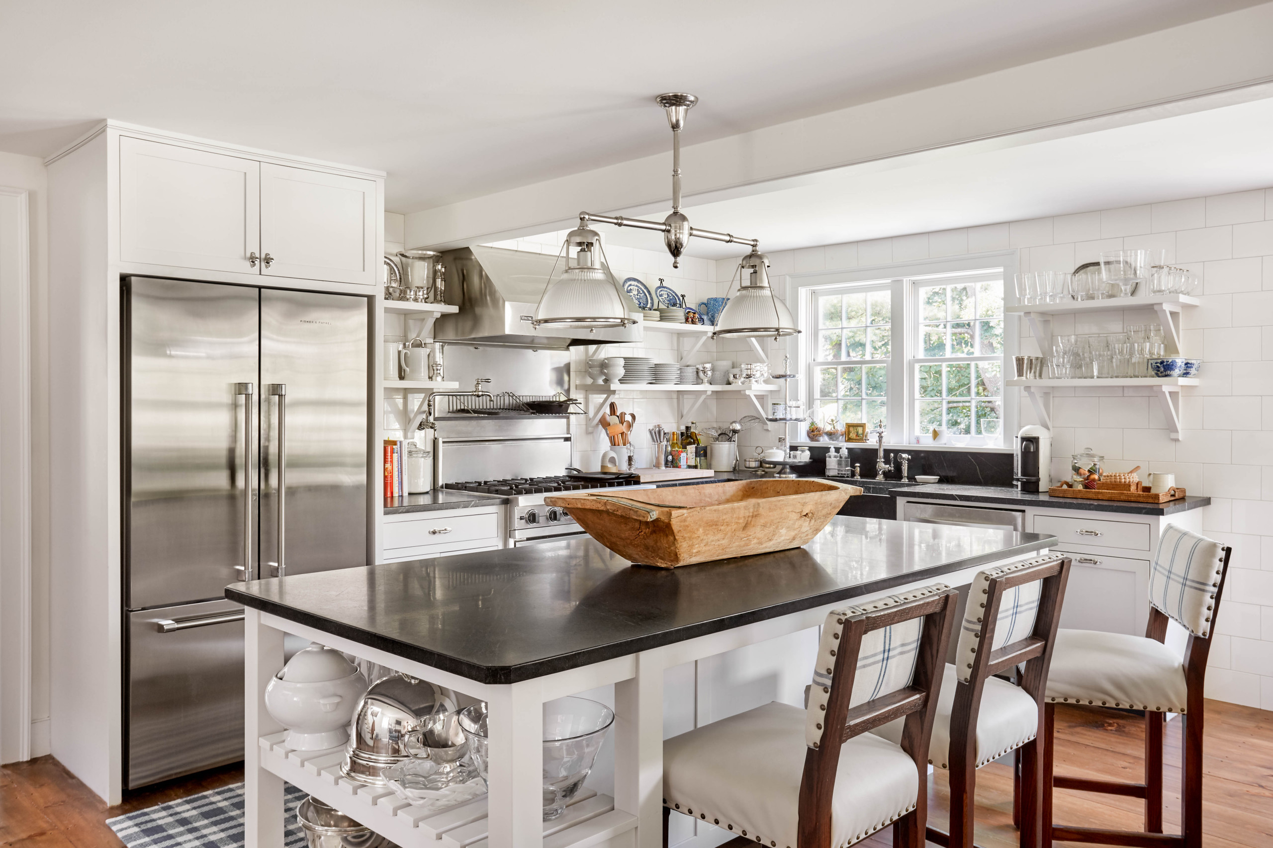 Modern farmhouse kitchen with black countertops, stainless steel appliances, and open shelving