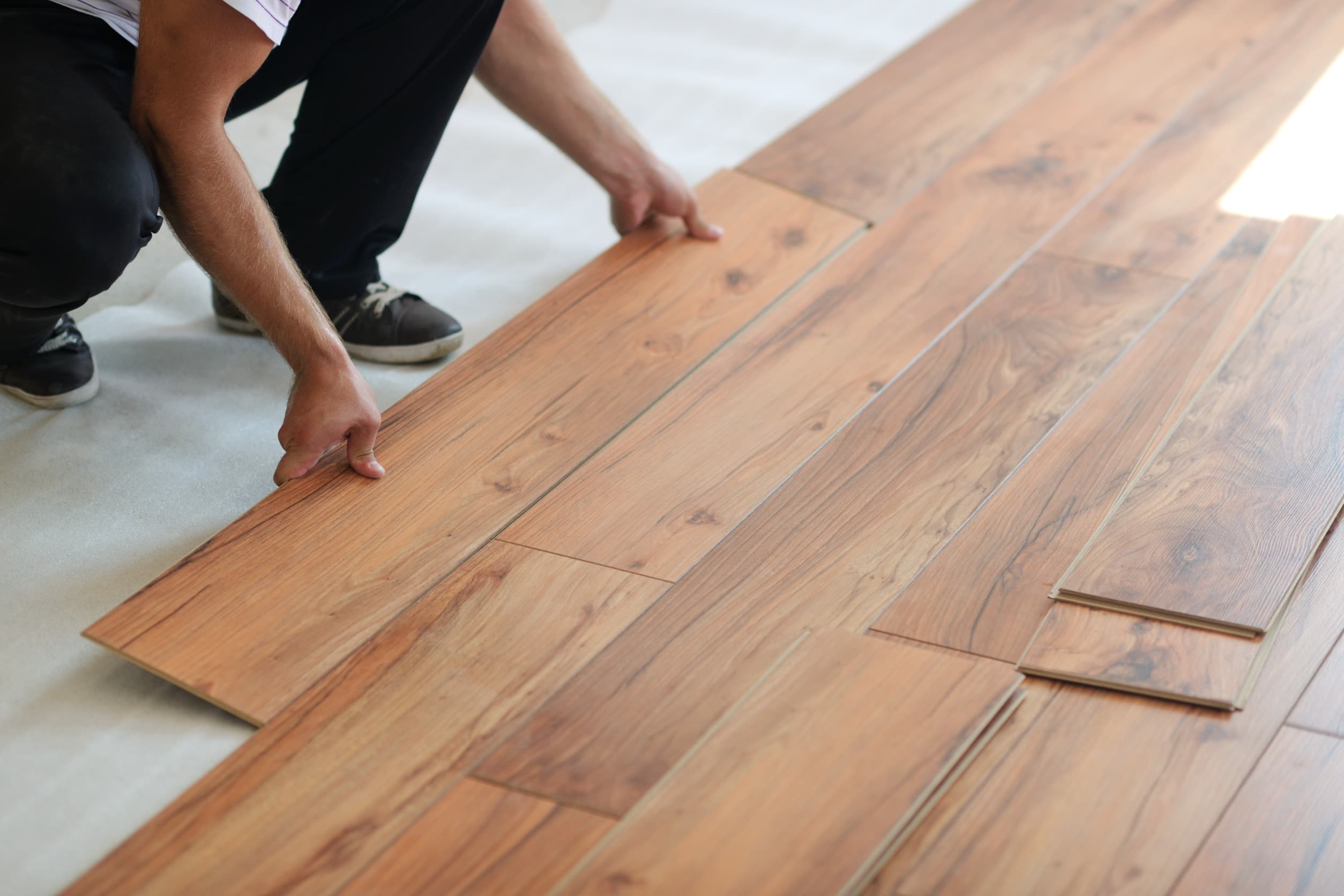 Worker installing wooden laminate flooring panels
