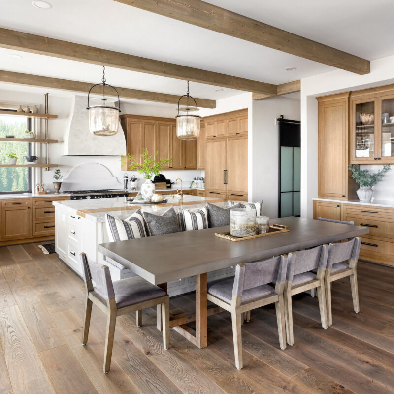 Rustic modern kitchen with wooden cabinets, dining table, and wide plank wood flooring