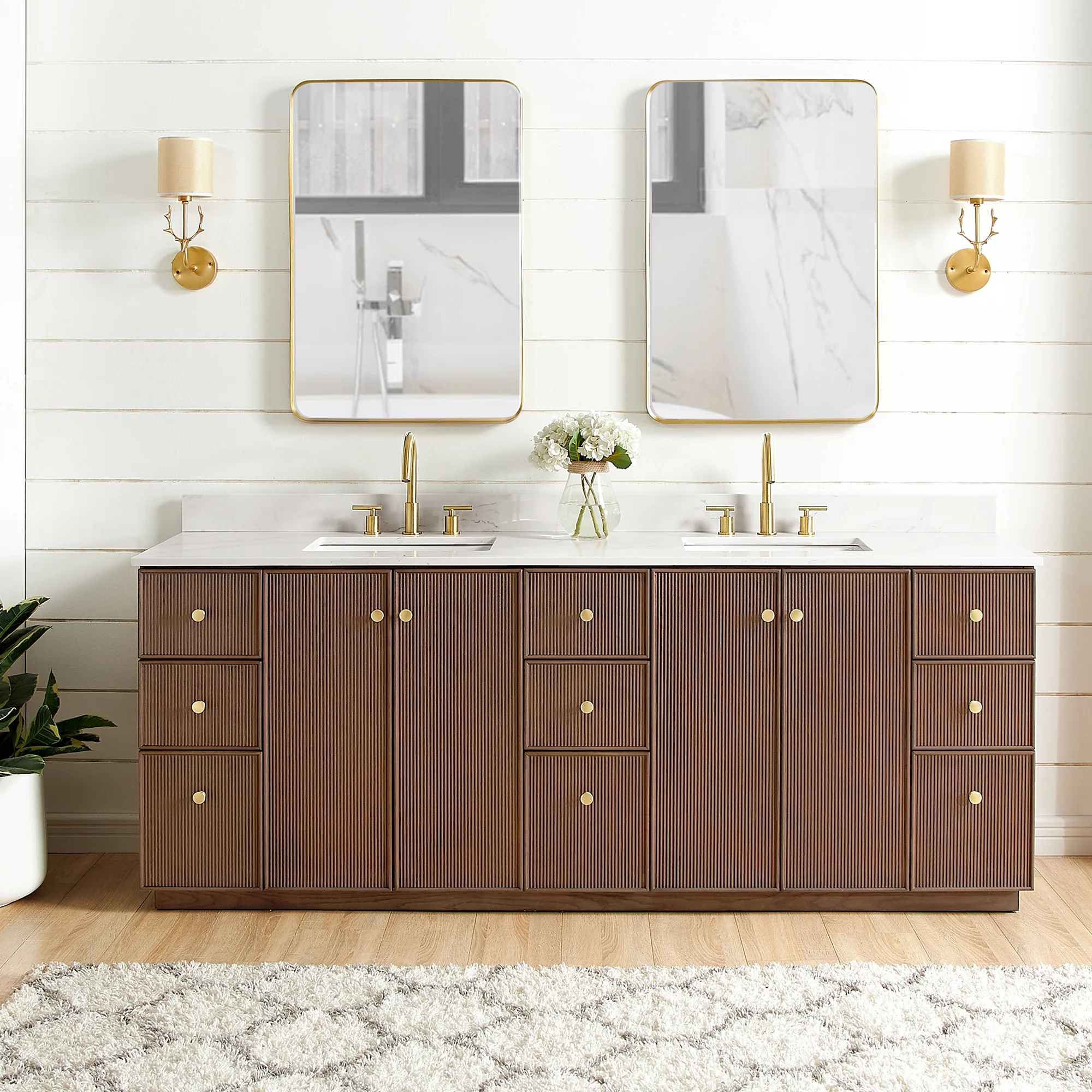 Double sink bathroom vanity with ribbed brown wood cabinetry, gold hardware, white countertop, and dual rectangular mirrors.