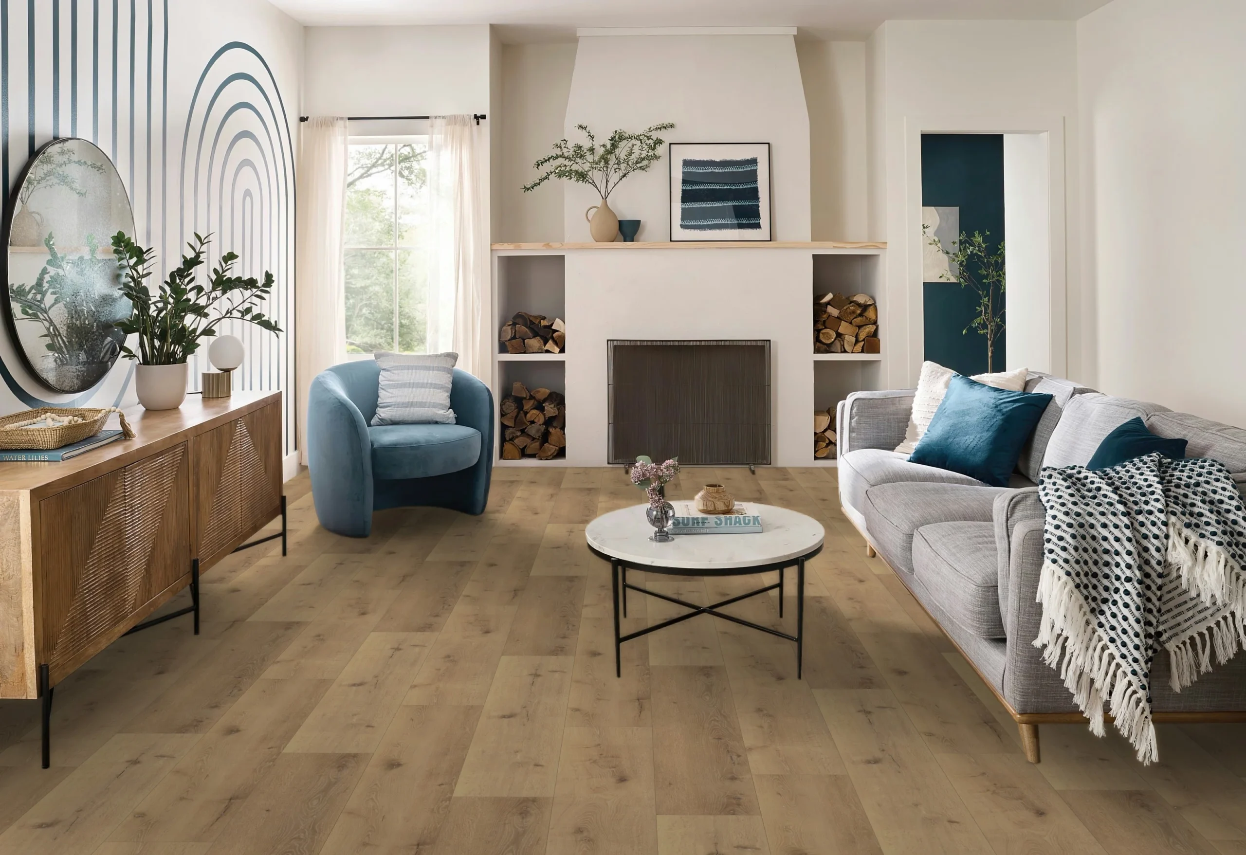 Stylish living room with light oak plank flooring, gray sofa, blue accent chair, round marble coffee table, and fireplace with wood storage.