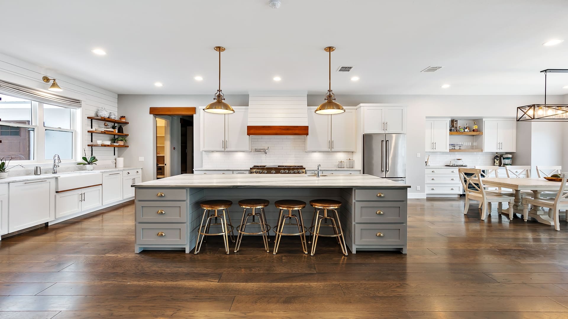 Luxury kitchen with a large island, wooden flooring, and white cabinetry