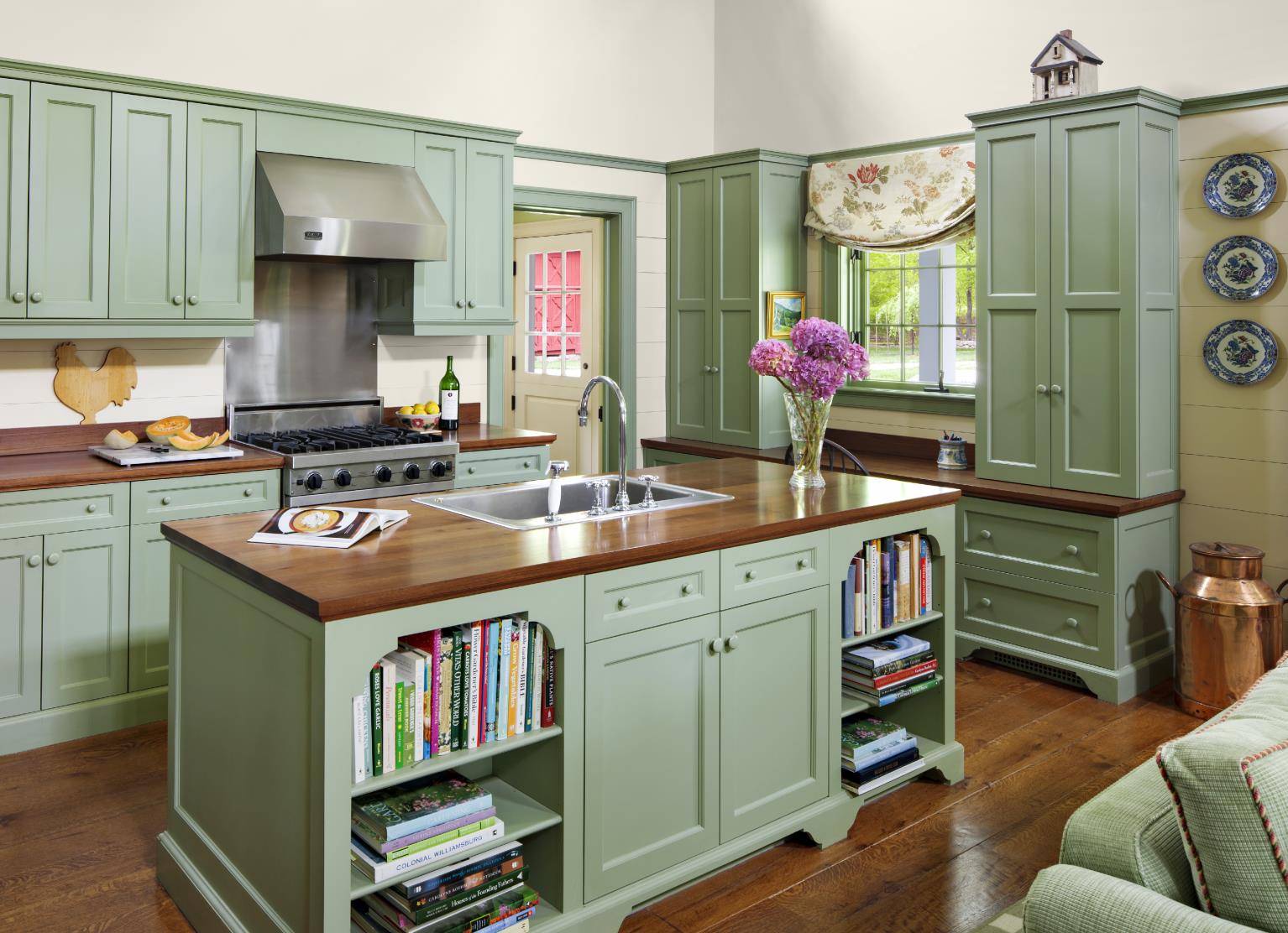 Rustic green kitchen with wood countertops, central island, and built-in bookshelves