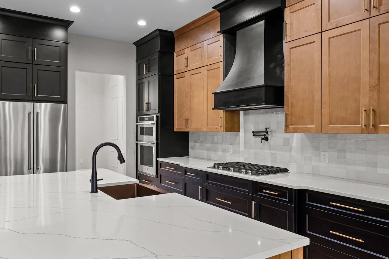  Contemporary kitchen featuring black and natural wood cabinets, quartz countertops, stainless steel appliances, and a matte black faucet.