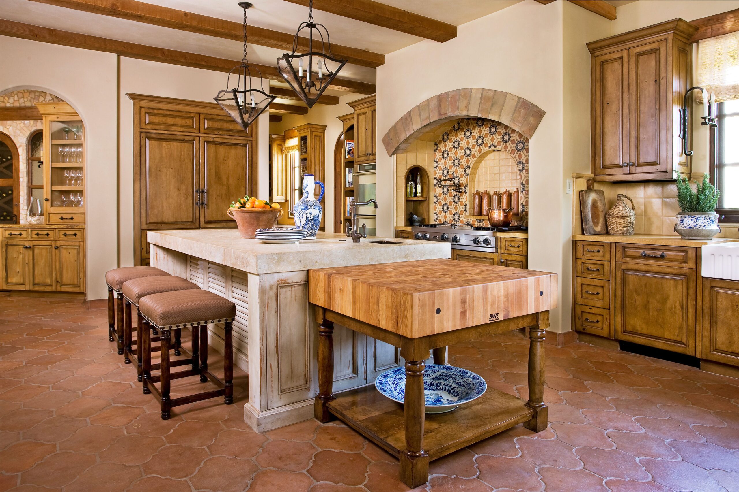 Rustic Mediterranean kitchen with wood cabinetry, tile backsplash, and large island.