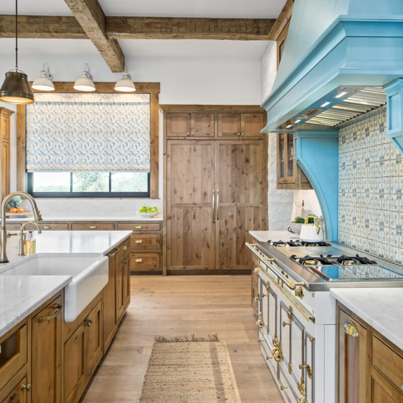 Rustic kitchen with wood cabinetry, white countertops, and a bold turquoise range hood