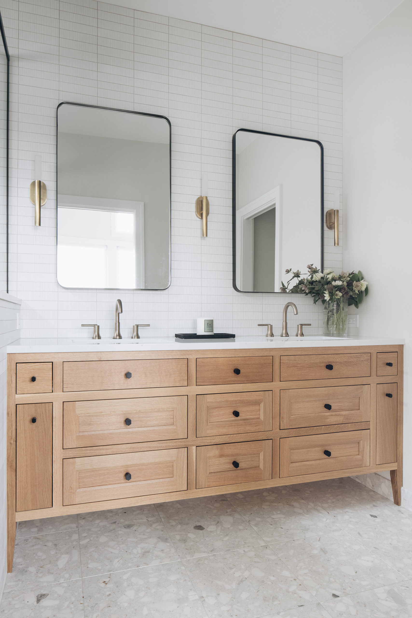 Minimalist bathroom vanity with natural wood cabinetry, dual sinks, and wall-mounted mirrors.