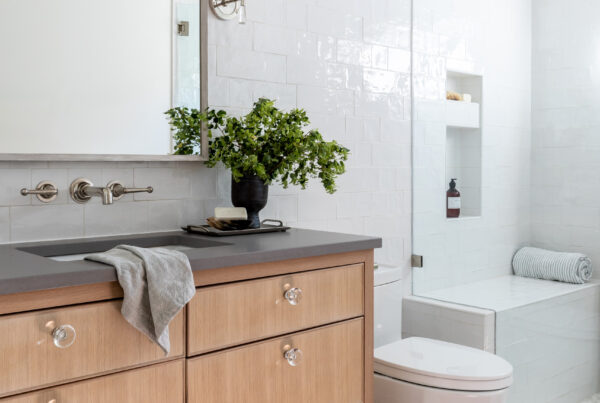 Modern bathroom with wood vanity, white tiled shower, and decorative rug.