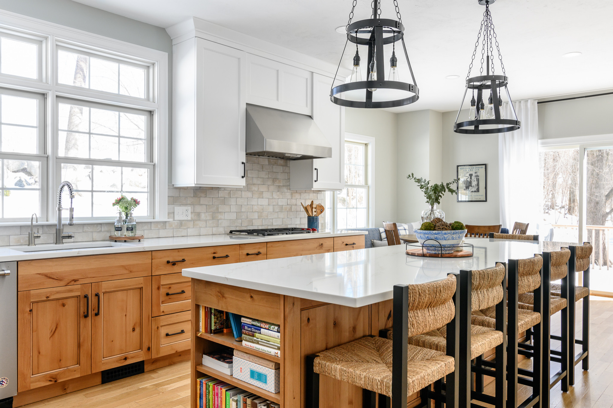Modern kitchen with white quartz island, natural wood cabinets, and woven bar stools.