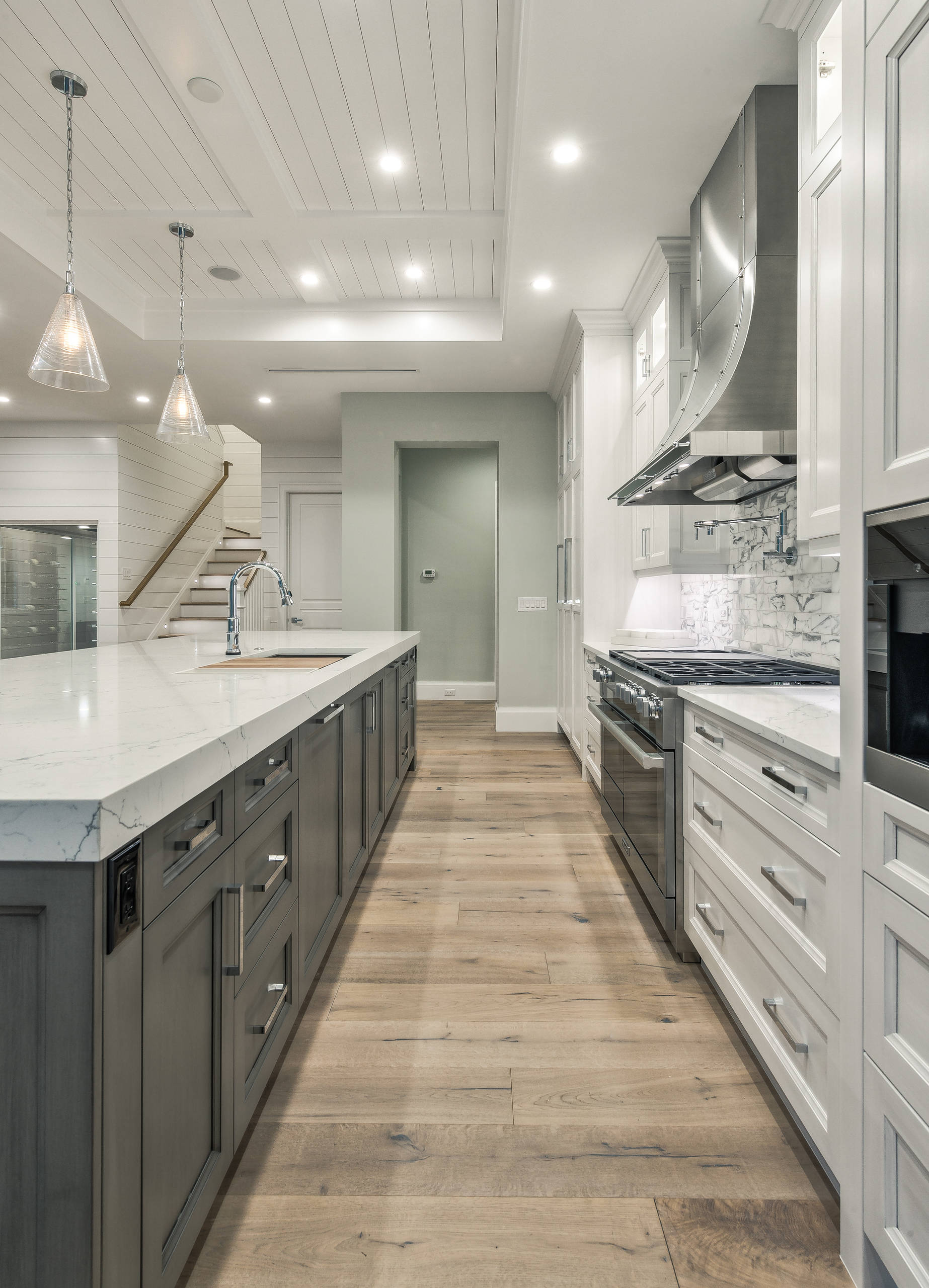 Modern kitchen with white cabinetry, marble countertops, and light wood flooring.