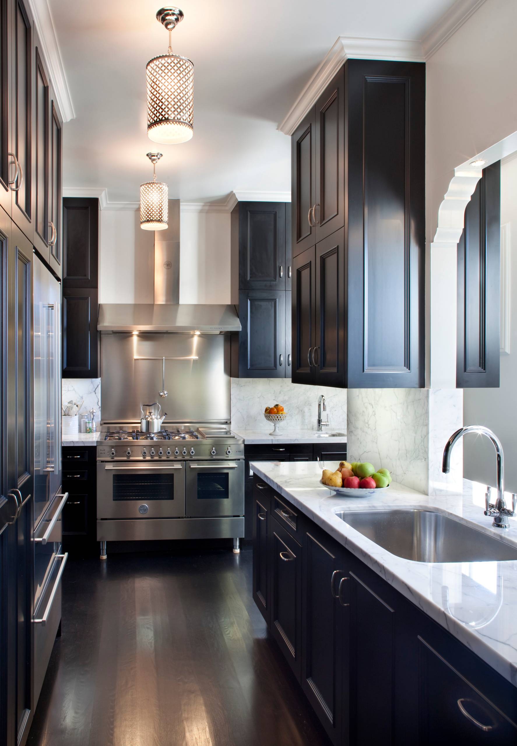 Modern galley kitchen with dark cabinets, marble countertops, and stainless steel appliances