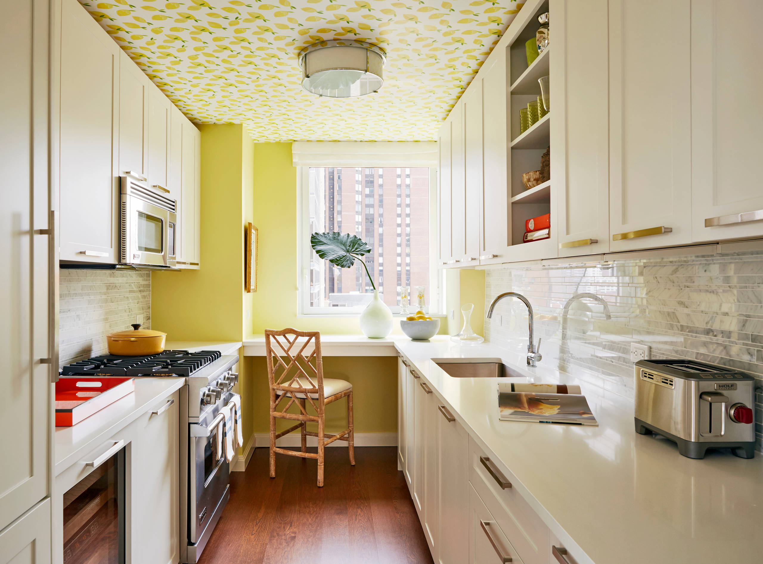 Bright galley kitchen with white cabinets, yellow walls, and patterned ceiling