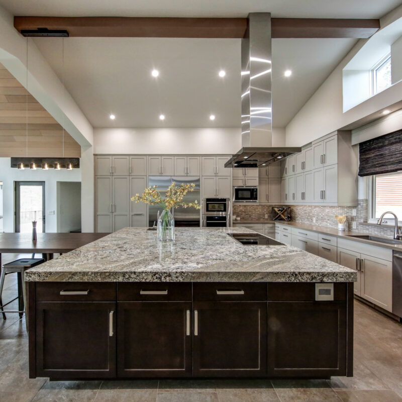 Luxury kitchen with granite island, stainless steel appliances, and modern lighting.