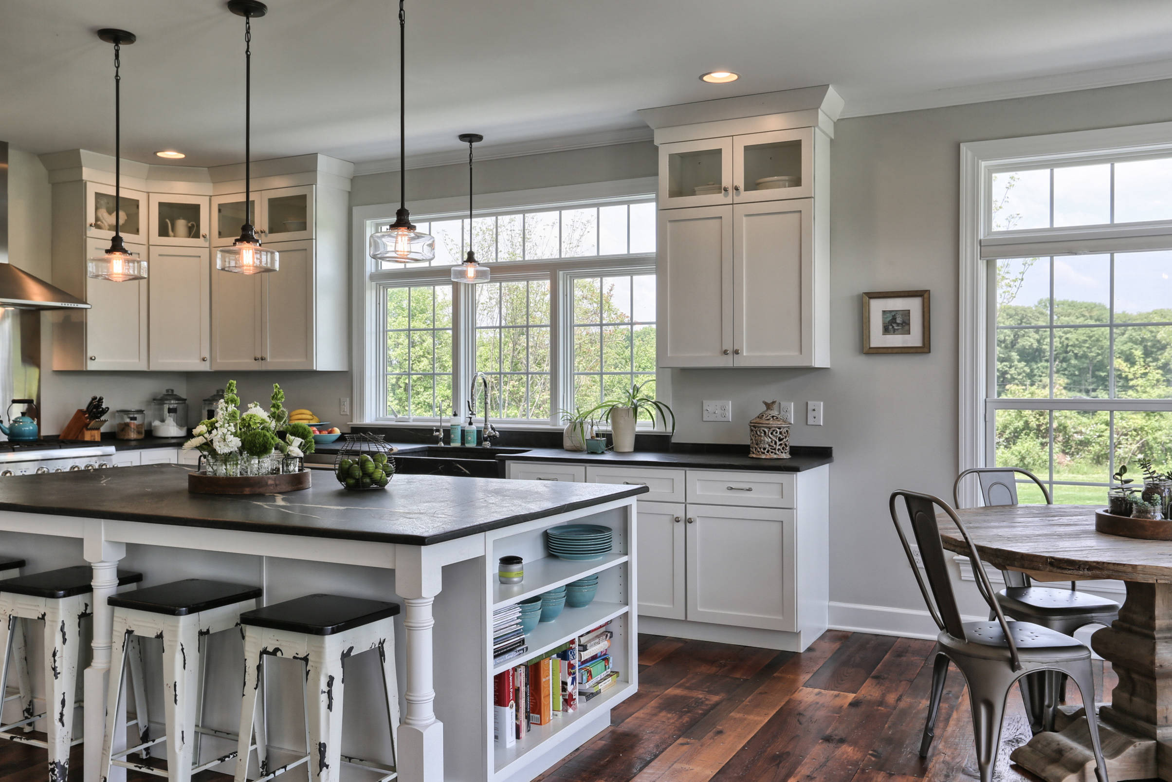 Farmhouse kitchen with black countertops, white cabinets, and rustic wood flooring