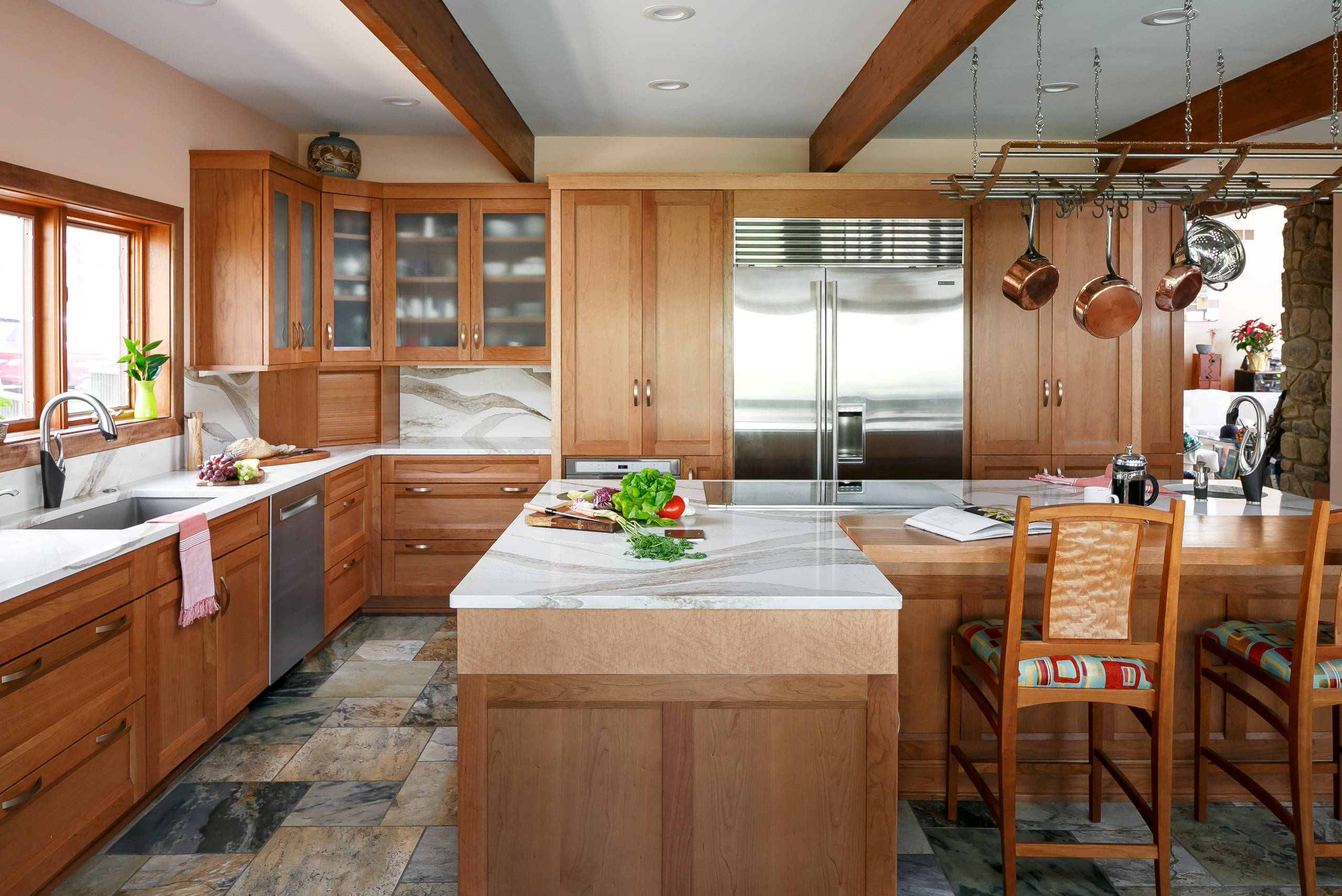 Spacious rustic kitchen with wood cabinetry, marble countertops, and stainless steel appliances