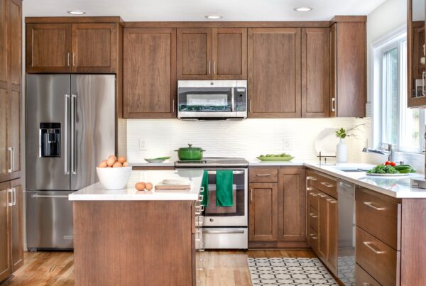 Modern kitchen with wooden cabinets, stainless steel appliances, and white countertops.