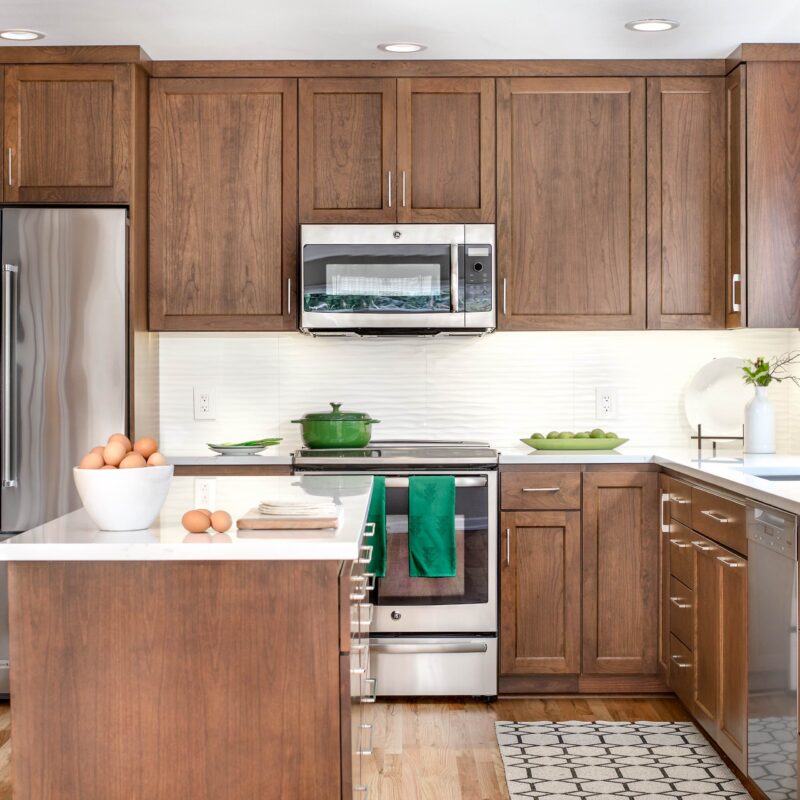 Modern kitchen with wooden cabinets, stainless steel appliances, and white countertops.