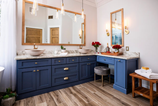 Luxury bathroom with navy blue cabinets, marble countertops, and modern lighting fixtures.