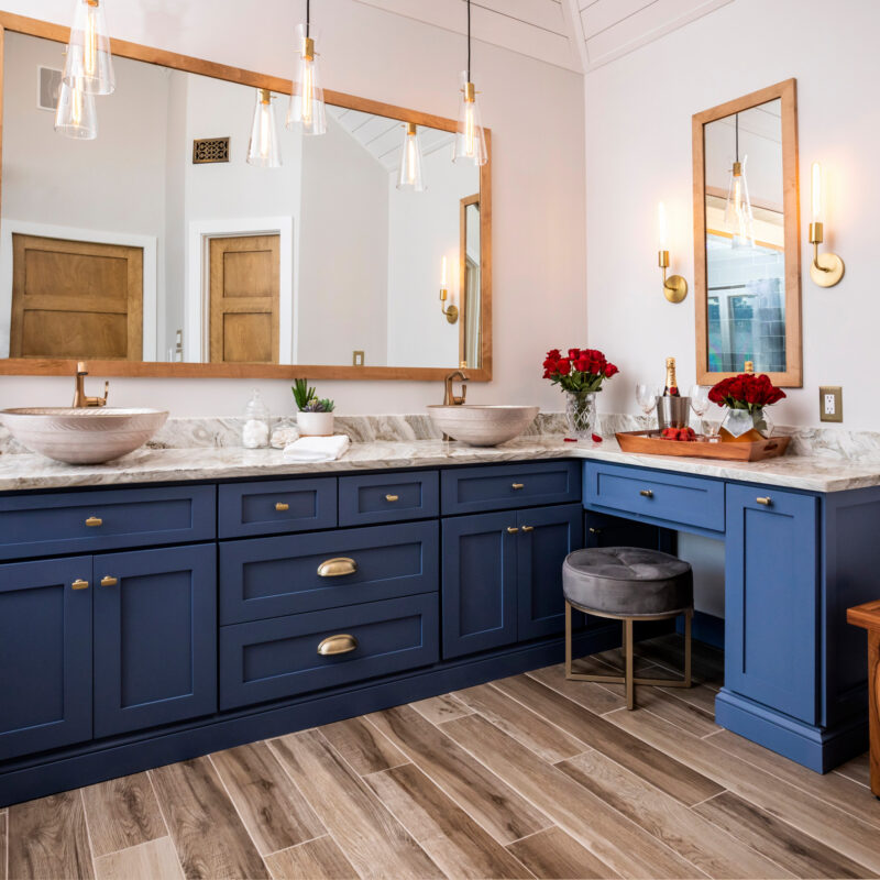 Luxury bathroom with navy blue cabinets, marble countertops, and modern lighting fixtures.