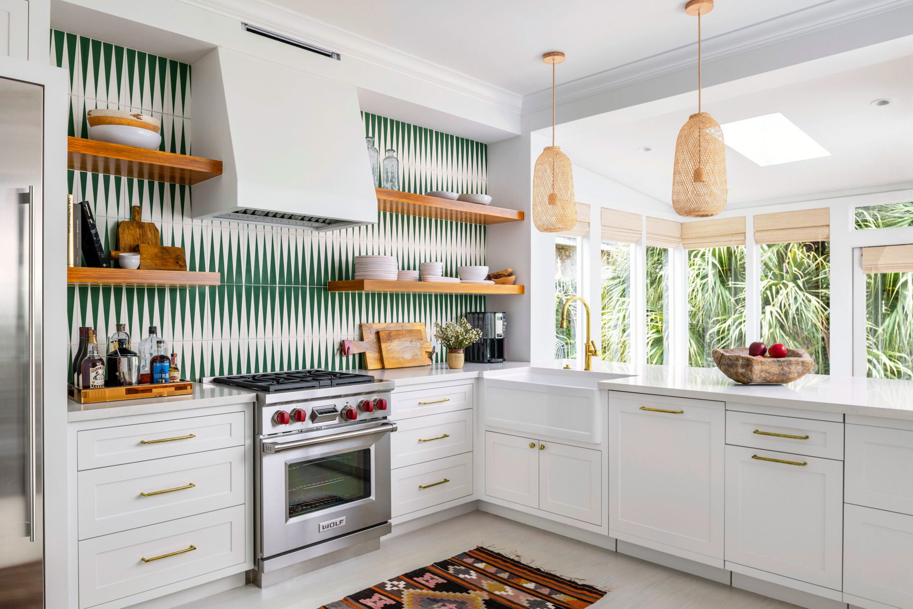 Modern white kitchen with patterned green backsplash and wooden open shelves.